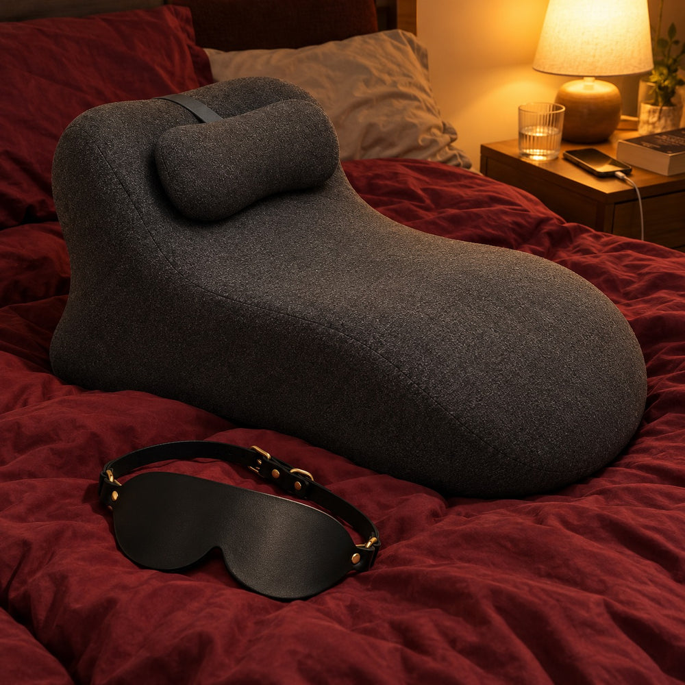 The gray WildNightX Pillow and the free blindfold on a dark red duvet