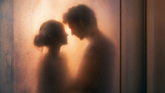 Soft silhouette of a couple behind a steamy fogged glass shower panel in warm light