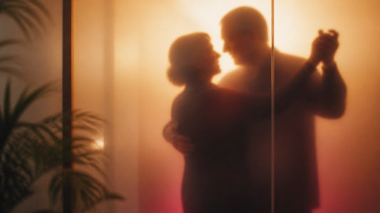 Silhouette of a mature couple slow dancing behind frosted glass in warm golden light, comfortable sex positions for older couples